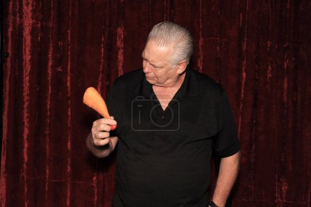 Photo for A man smiles as he shows off his Plastic Chicken Leg while having his picture taken in a Photo Booth - Royalty Free Image