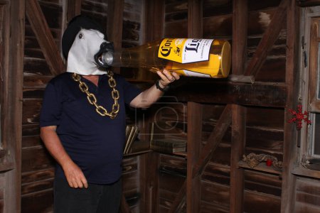 Téléchargez les photos : Lake Forest, Californie - États-Unis - 6 septembre 2023 : Un homme masqué au cheval tient une bouteille de bière Corona gonflable pendant qu'il sourit et pose pour que ses photos soient prises dans une cabine photo. Les photomaton sont amusants. - en image libre de droit