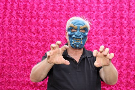 Photo for A man in blue scary mask poses for his picture to be taken while in a Photo Booth at a Party. - Royalty Free Image