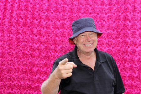 Photo for Handsome middle aged man in hat posing for his picture to be taken while in a photo booth at a party - Royalty Free Image