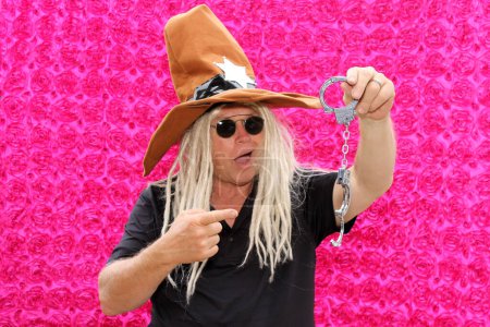 Photo for A man wears crazy props and poses for his picture to be taken in a photo booth at a party - Royalty Free Image