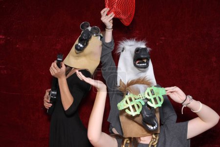 Téléchargez les photos : Les personnes non identifiables portent des masques de tête de cheval et posent et jouent pendant que leurs photos sont prises dans une cabine photo. - en image libre de droit