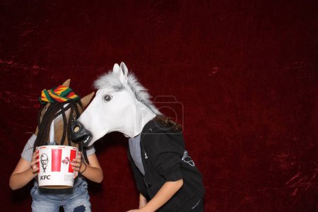 Téléchargez les photos : Les personnes non identifiables portent des masques de tête de cheval et posent et jouent pendant que leurs photos sont prises dans une cabine photo - en image libre de droit