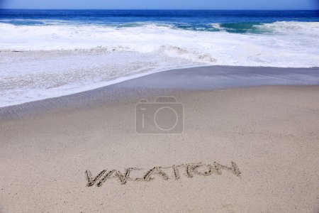 Téléchargez les photos : Le mot VACATION écrit dans le sable sur la plage avec l'océan comme arrière-plan. - en image libre de droit