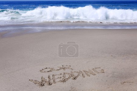 Foto de Palabras Nuestra boda escrita en la arena en la playa con la marea oceánica y las olas del océano - Imagen libre de derechos