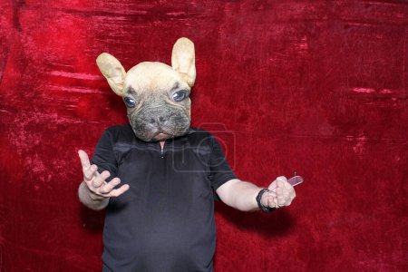 Foto de Un hombre lleva una máscara de perro y posa para que sus fotos sean tomadas mientras está en una cabina de fotos en una boda o fiesta. - Imagen libre de derechos