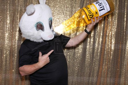 Photo for Lake Forest, California - USA - May 15, 2016. A man holds a Inflatable Corona Beer Bottle while he smiles and poses for his pictures to be taken while in a Photo Booth. Photo Booths are fun for all. - Royalty Free Image