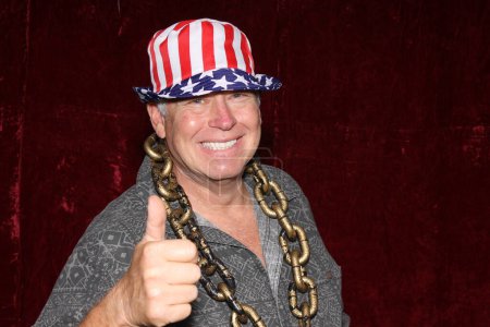 Téléchargez les photos : Photo Booth. Un homme portant un chapeau de drapeau américain montre le pouce vers le haut signe et sourit pendant qu'il se fait prendre en photo dans une cabine de photo à une fête. - en image libre de droit
