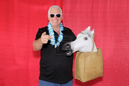 Téléchargez les photos : Un homme avec un masque de tête de cheval en caoutchouc pose dans une cabine photo. - en image libre de droit
