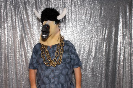 Foto de Un hombre con una máscara de cabeza de caballo de goma posa en una cabina de fotos. - Imagen libre de derechos