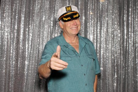 Photo for Photo Booth. Man wearing a Captains Hat. A man enjoys wearing a Captains Hat while having his pictures taken in a Photo Booth at a Party on a Yacht. People on Yachts love Photo Booths. Happy Sailing. - Royalty Free Image