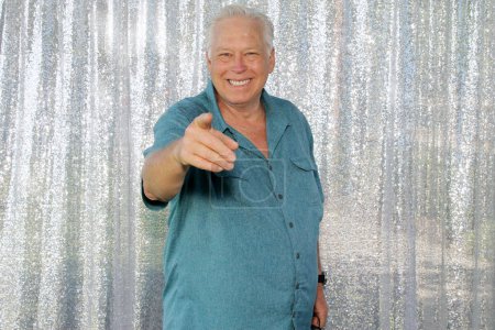 Photo for A man Smiles and points at camera for his pictures to be taken while in a Photo Booth at a Wedding or Party. - Royalty Free Image