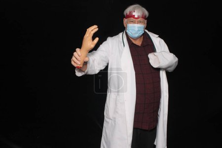 Téléchargez les photos : Un docteur maléfique pose alors qu'il se fait prendre en photo dans une cabine photo d'Halloween avec des rideaux de velours noir. Méfiez-vous des mauvais médicaments. - en image libre de droit