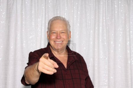 Photo for A smiling man points at camera and poses for his pictures to be taken while in a Photo Booth at a Wedding. Photo Booths are popular at Weddings, Birthdays and all events both Public and Private. Fun Times. - Royalty Free Image