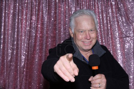 Photo for Lounge Singer. Photo Booth. A man with a Microphone Sings and Tells Jokes to entertain the crowd while he is in a Photo Booth waiting for his Pictures to be taken. Photo Booths are great for parties. - Royalty Free Image
