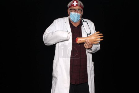 Téléchargez les photos : Médecin. Un docteur est choqué quand il découvre que sa main gauche s'est séparée de son bras avec un fond noir. Méfiez-vous de la mauvaise médecine. Costume d'Halloween. Kiosque photo Halloween. Urgence médicale - en image libre de droit