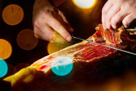 Photo for Slicing Spanish beric ham. Spanish jamon and traditional food. Dry Spanish ham, Jamon Serrano, Bellota, Italian Prosciutto Crudo or Parma ham. - Royalty Free Image