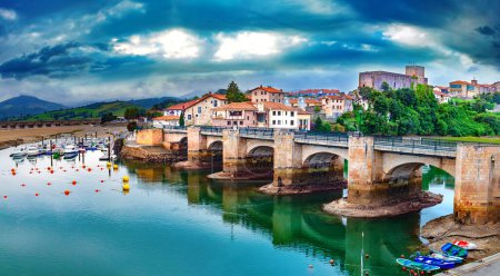 Scenic mountain and sea panoramic landscape in northern Spain.Green meadows and boats in the port under the medieval stone bridge. San Vicente de la barquera village in Cantabria,Spain.