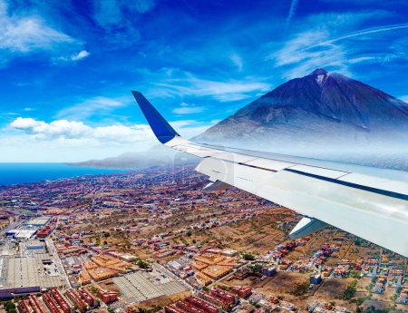 Photo for Aerial view of the sky over the mountains and the peak of the Teide volcano from the window of an airplane.Canary island, Tenerife,Spain.Town scenery above the clouds. - Royalty Free Image
