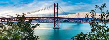 Photo for Panoramic photograph of the 25 de Abril bridge in the city of Lisbon over the Tajo River.Lisbon landscape at sunset. - Royalty Free Image