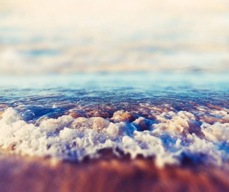 Téléchargez les photos : Détail du littoral et du sable.Paysage marin et vagues se brisant sur la côte.Coucher de soleil pittoresque abstrait sur la plage. - en image libre de droit