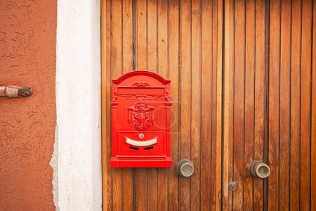 Téléchargez les photos : Vintage red mailbox hanging on a wooden door at a house on the street waiting for mail to be delivered - en image libre de droit
