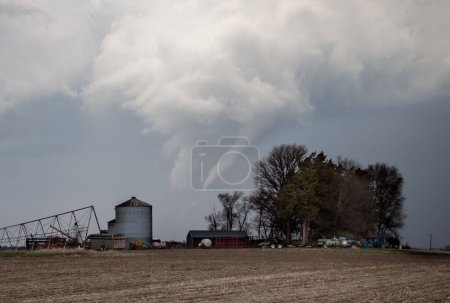 Photo for A tornado reaches down from a storm cloud behind a farm in the rural countryside. - Royalty Free Image