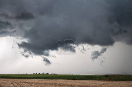 Téléchargez les photos : Un nuage de paroi basse se rassemble sous une tempête violente, avec des champs agricoles en dessous. - en image libre de droit