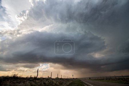 Photo for A supercell thunderstorm rotates in the sky over an empty highway in the plains. - Royalty Free Image