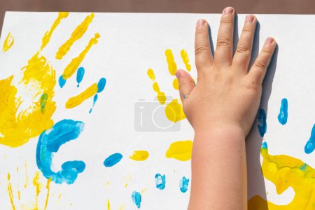 Téléchargez les photos : Bright prints of children's hands from paint on the wall, background, texture, horizontal format. - en image libre de droit