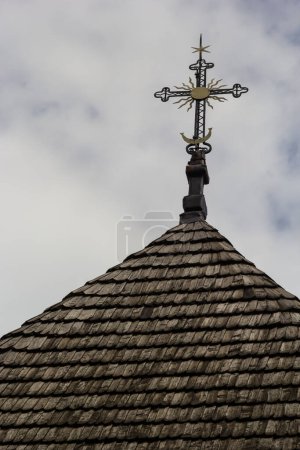 Photo for Old wooden church against the blue sky in Ukraine, wooden roof with a cross. - Royalty Free Image
