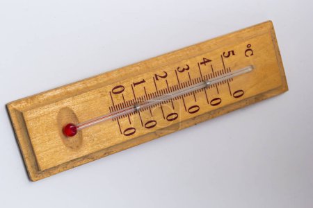 Foto de Termómetro de la habitación sobre una base de madera de cerca sobre un fondo blanco. Escala de grados Celsius. - Imagen libre de derechos