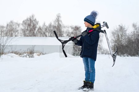 Téléchargez les photos : Garçon dans un parc d'hiver. Garçon avec scooter de neige. - en image libre de droit
