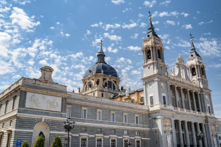 Téléchargez les photos : Vue latérale de la cathédrale Sainte-Marie-la-Royale de La Almudena sur fond de ciel bleu avec des nuages blancs en été à Madrid, Espagne. Madrid est une destination touristique populaire d'Europe
. - en image libre de droit
