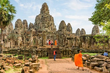 Foto de Siem Reap, Camboya - 4 de mayo de 2015: Monje budista que viene en el antiguo templo de Bayon en Angkor Thom. Enigmático Angkor Thom es un destino popular de turistas y peregrinos. - Imagen libre de derechos