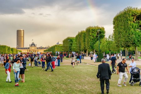 Photo for Paris, France - August 13, 2014: Crowds of tourists and residents rest and take pictures on the Champ de Mars (Fild of Mars). The public greenspace is a popular tourist attraction of Europe. - Royalty Free Image