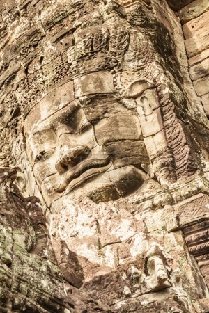 Photo for Giant stone face of ancient Bayon temple. Bayon temple nestled in Angkor Thom, Siem Reap, Cambodia. Angkor Thom is a popular tourist attraction. - Royalty Free Image