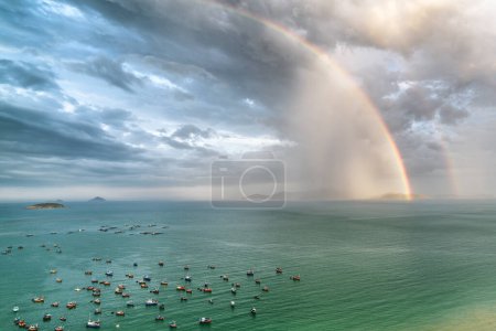 Téléchargez les photos : Impressionnant double arc-en-ciel au-dessus de la baie de Nha Trang de la mer de Chine méridionale, Vietnam. Vue aérienne incroyable des bateaux de pêche vietnamiens traditionnels dans la baie. L'île de Hon Tre est visible en arrière-plan. - en image libre de droit