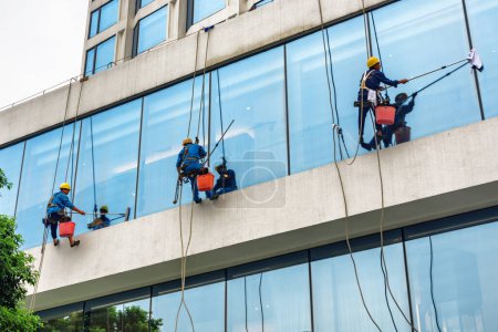 Téléchargez les photos : Guangzhou, Chine - 7 novembre 2015 : Les grimpeurs industriels nettoient les fenêtres des immeubles de grande hauteur. Guangzhou est une destination touristique populaire de l'Asie. - en image libre de droit