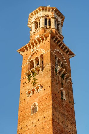 The Torre dei Lamberti in Verona (Italy) in morning sun. Clock tower on blue sky background. Verona is a popular tourist destination of Europe.