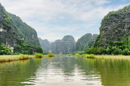 Awesome view of natural karst towers reflected in water of the Ngo Dong River at the Tam Coc portion, Ninh Binh Province, Vietnam. The Tam Coc is a popular tourist attraction in Asia.