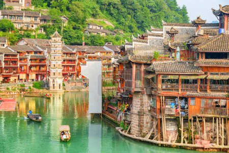 Photo for Amazing view of traditional wooden tourist boats on the Tuojiang River (Tuo Jiang River) in Phoenix Ancient Town (Fenghuang County), China. The Wanming Pagoda is visible at left. - Royalty Free Image