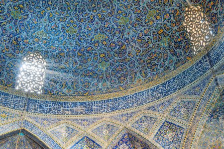 Foto de Isfahán, Irán - 24 de octubre de 2018: Increíble vista de la ventana tallada en piedra y el juego de luces dentro de la Mezquita Seyyed. Paredes cubiertas de coloridos mosaicos e inscripciones caligráficas. Arquitectura islámica. - Imagen libre de derechos