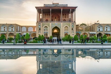 Foto de Isfahán, Irán - 24 de octubre de 2018: Impresionante vista del Palacio Ali Qapu en la Plaza Naqsh-e Jahan al atardecer. La fachada reflejada en el agua. La plaza es una atracción turística popular de Oriente Medio. - Imagen libre de derechos