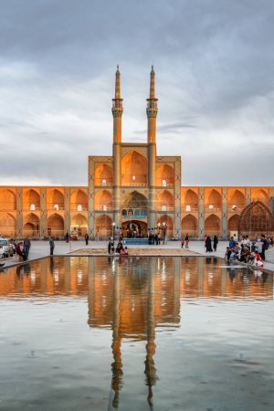 Téléchargez les photos : Yazd, Iran - 26 octobre 2018 : Vue panoramique du complexe Amir Chakhmaq reflétée dans le réservoir d'eau au milieu de la place de la ville historique de Yazd au coucher du soleil. Architecture persane unique. - en image libre de droit
