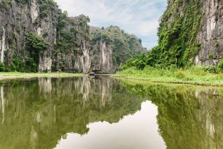 Awesome view of natural karst towers reflected in water of the Ngo Dong River at the Tam Coc portion, Ninh Binh Province, Vietnam. The Tam Coc is a popular tourist attraction in Asia.