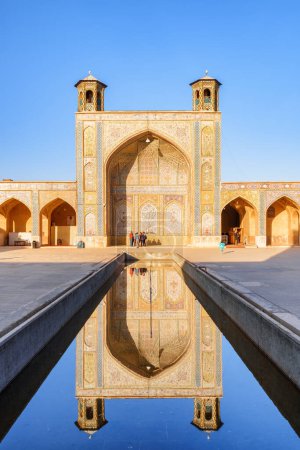 Foto de Impresionante vista del iwan norte reflejado en el depósito de agua en el centro del patio de la mezquita Vakil en Shiraz, Irán. El lugar musulmán es una atracción turística popular de Oriente Medio. - Imagen libre de derechos