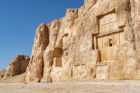 Amazing ancient necropolis Naqsh-e Rustam on blue sky background in Iran. Large tombs belonging to Achaemenid kings carved out of rock face at considerable height above the ground.