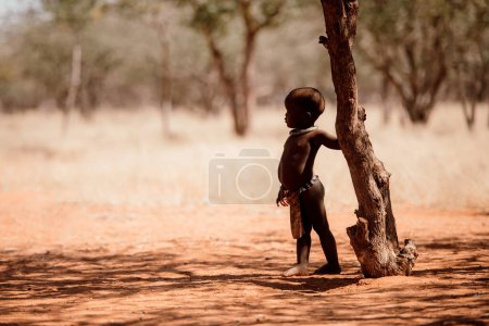 Téléchargez les photos : OPUWO, RÉGION D'OTJIWARONGO NAMIBIE - 4 MAI 2021 : Jeune garçon Himba non identifié avec les colliers typiques dans Himba musée vivant lors d'une apparition devant les touristes - en image libre de droit