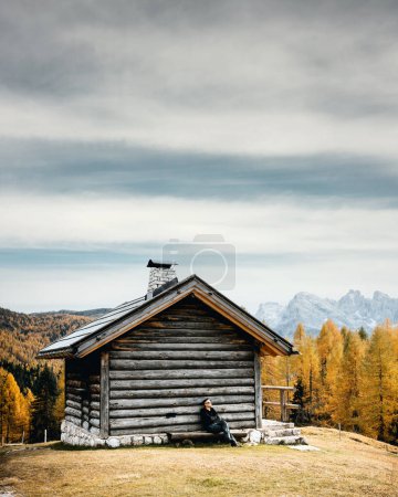 Téléchargez les photos : Incredible autumn view at Valfreda valley in Italian Dolomite Alps. Wooden cabin, yellow grass, orange larches forest and snowy mountains peaks on background. Dolomites, Italy. Landscape photography - en image libre de droit
